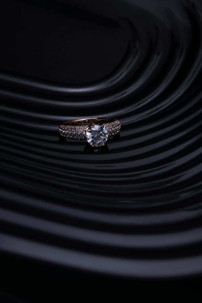 Close-up of a diamond ring with a dark, wavy background creating a luxurious and elegant atmosphere.